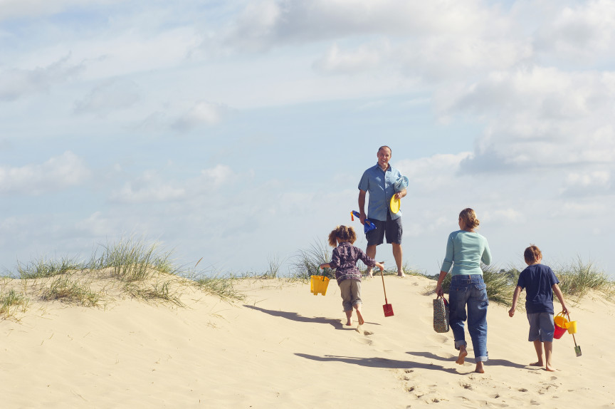 Family walking over beach dunes