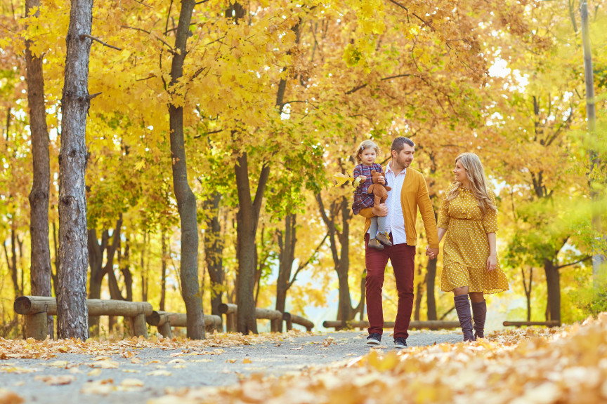 Young family walking through autumnal park